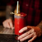 barman-with-a-glass-of-salty-red-tomato-bloody-mary-cocktail-with-picture-id1098019556