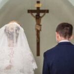 bride-and-groom-stand-before-crucifix-in-church-2-picture-id511028740